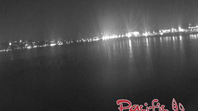 Marseille bay at night — lights along curved shoreline reflected as vertical pillars in calm Mediterranean water