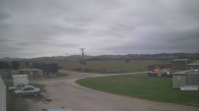 Rural gliding club airfield — flat green paddocks, low hills, hangars, overcast grey sky, Gippsland Victoria