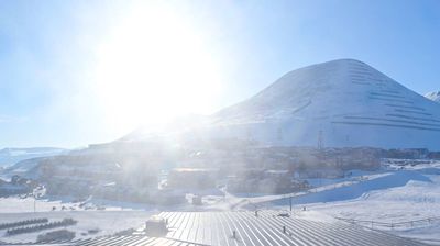 Longyearbyen, Svalbard -- snow-covered mountains under a low sun, small settlement buildings, high Arctic landscape, brilliant winter light