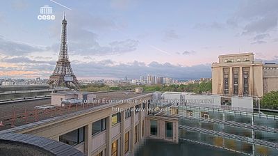 Webcam view of the Eiffel Tower at dawn from the CESE building, reflective pools on rooftop, pink and blue sky, early morning Paris