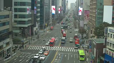 Donggyo-dong samgeori intersection, Seoul — overcast morning, red buses, LED billboards