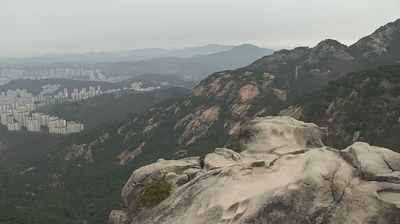 Granite peak of Bukhansan with apartment blocks far below in haze
