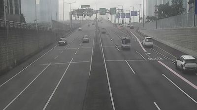 Wide expressway with sparse traffic, concrete barriers, toll gates, towers in mist