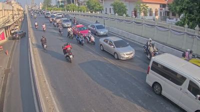 Motorcycles and cars weaving across bridge in golden afternoon light, fluid traffic