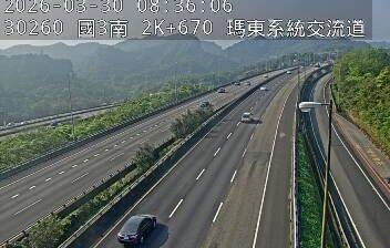 Highway carved through lush tropical hillside, vegetation pressing in from both sides