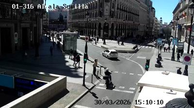 Madrid Alcala-Sevilla intersection, long afternoon shadows, people crossing, someone on a mobility scooter, grand buildings