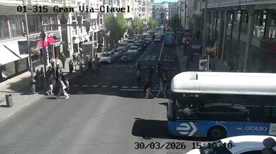 Madrid Gran Via at Clavel street, pedestrians crossing near a bus, traffic lights, street-level view
