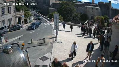 Dubrovnik Pile Gate entrance — pedestrians walking through the medieval gate, stone walls, street-level view with visible faces and postures