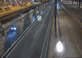 Barcelona port road at night — split-level highway, stone arched viaduct below, modern road above, one car's headlights