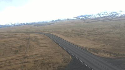 Route 1 curving through vast brown tundra toward Eyjafjallajökull glacier, snow-capped mountains, empty landscape